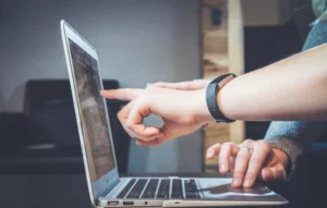 Two people pointing at a laptop after implementing a managed reporting system